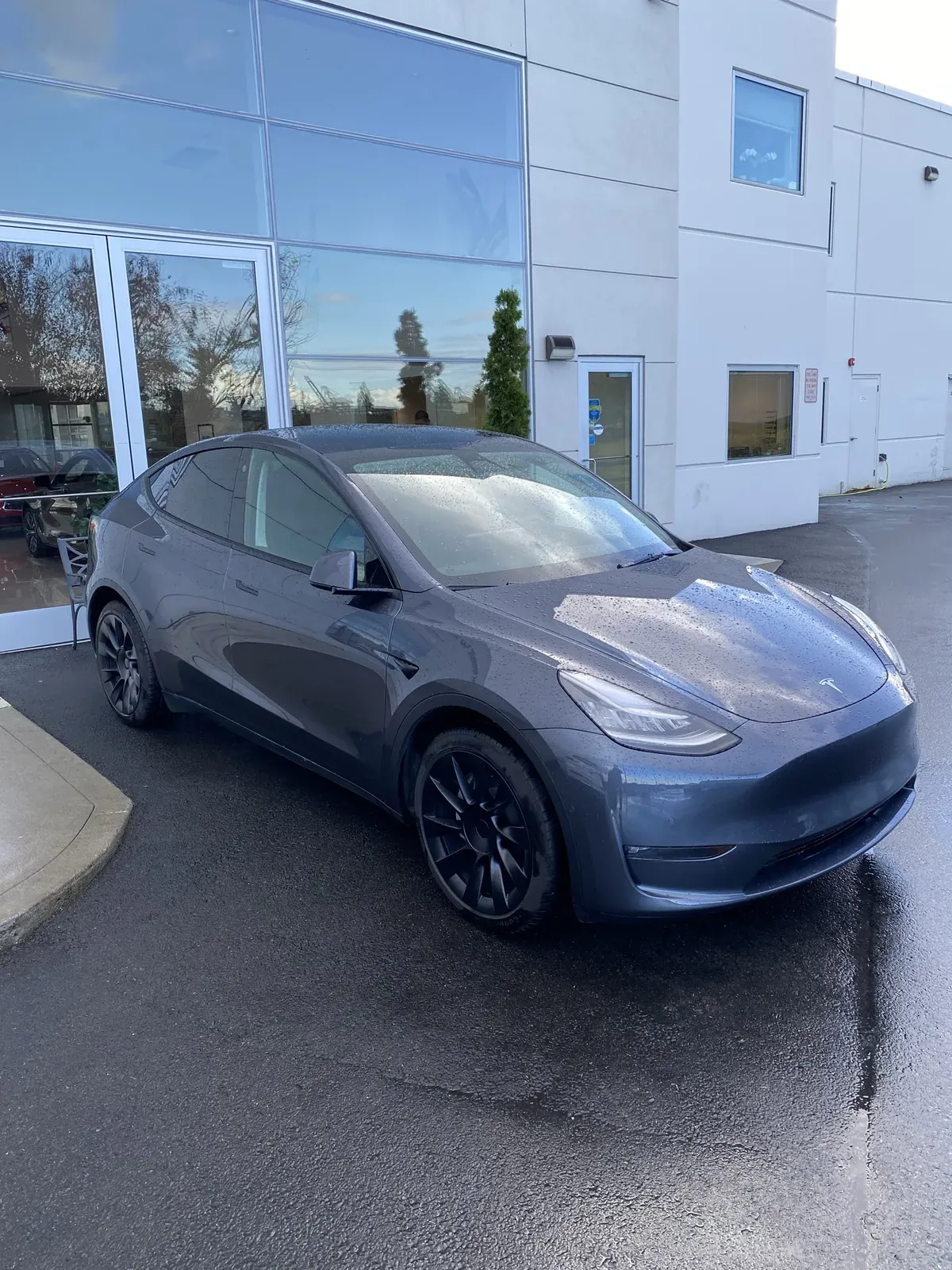 Gray Model Y with black wheels on a wet day