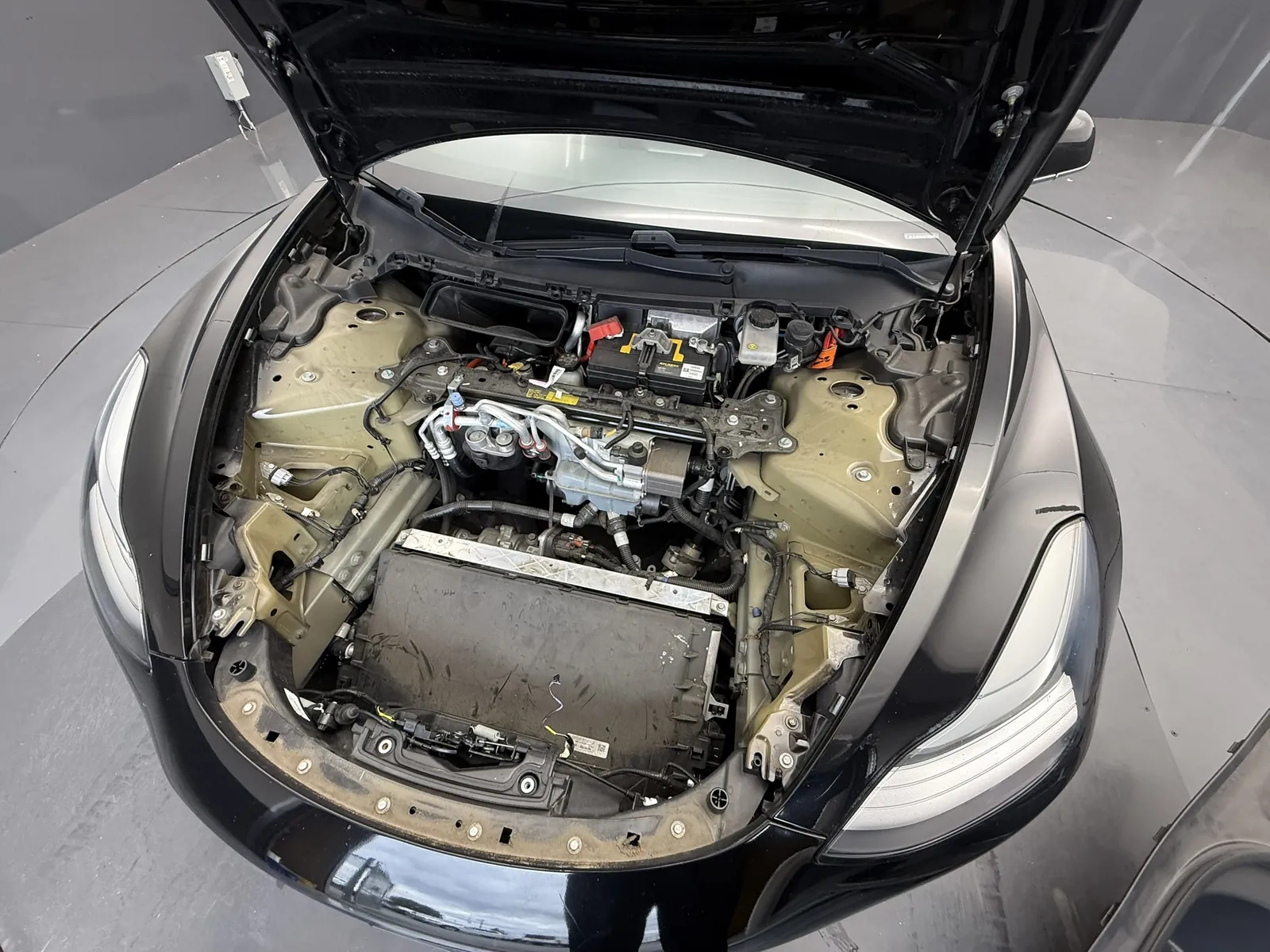 Overhead view into a Model 3 front compartment with the frunk tub removed, showing the radiator/condenser area and lower bumper beam